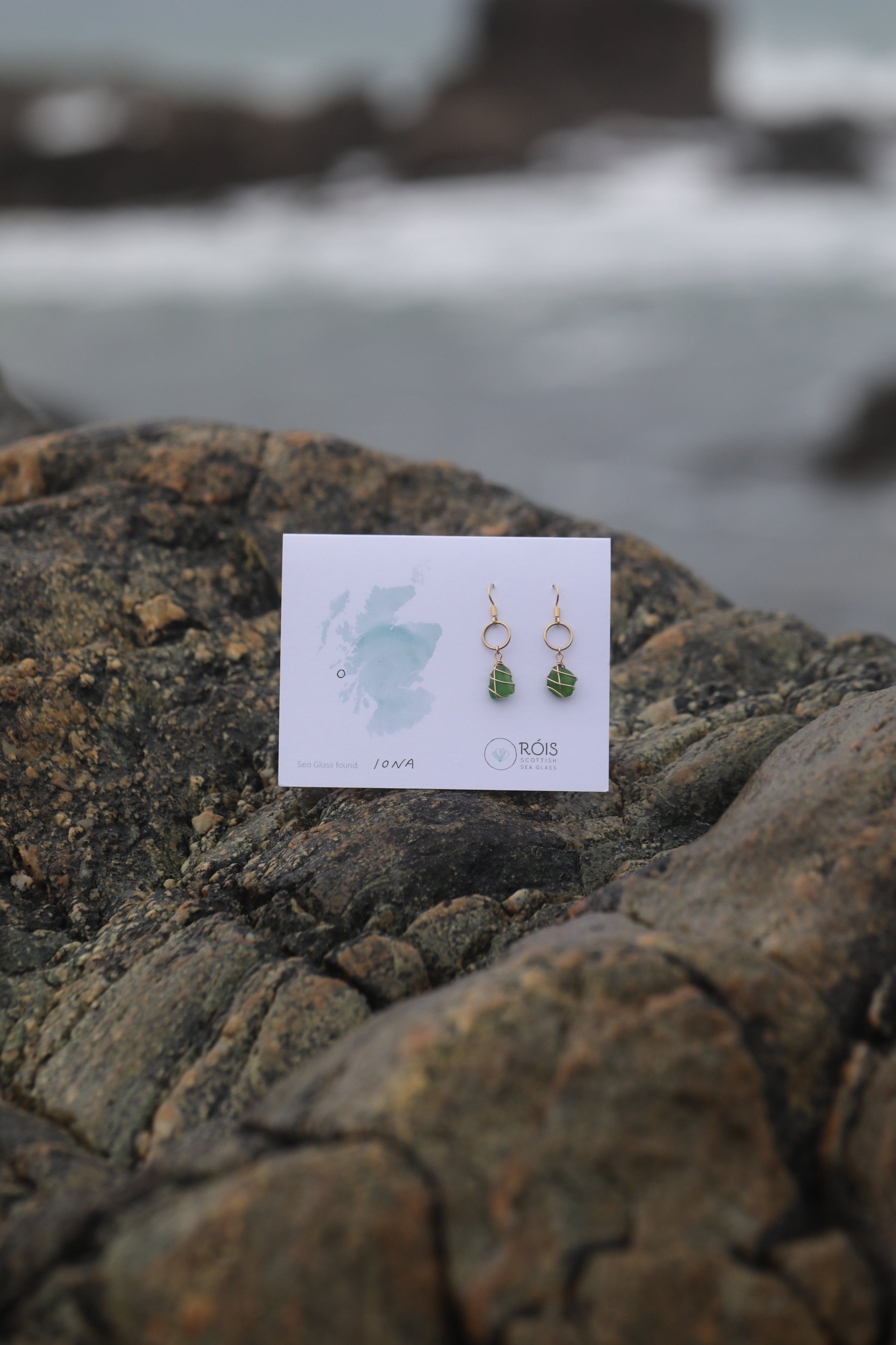Pair of earrings on a card against a textured stone background